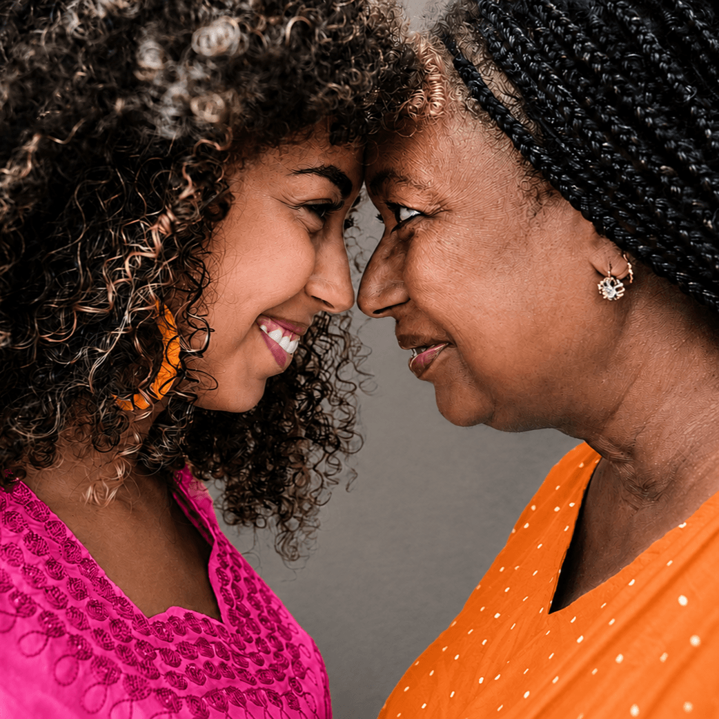 Two women connecting forehead to forehead with warm smiles